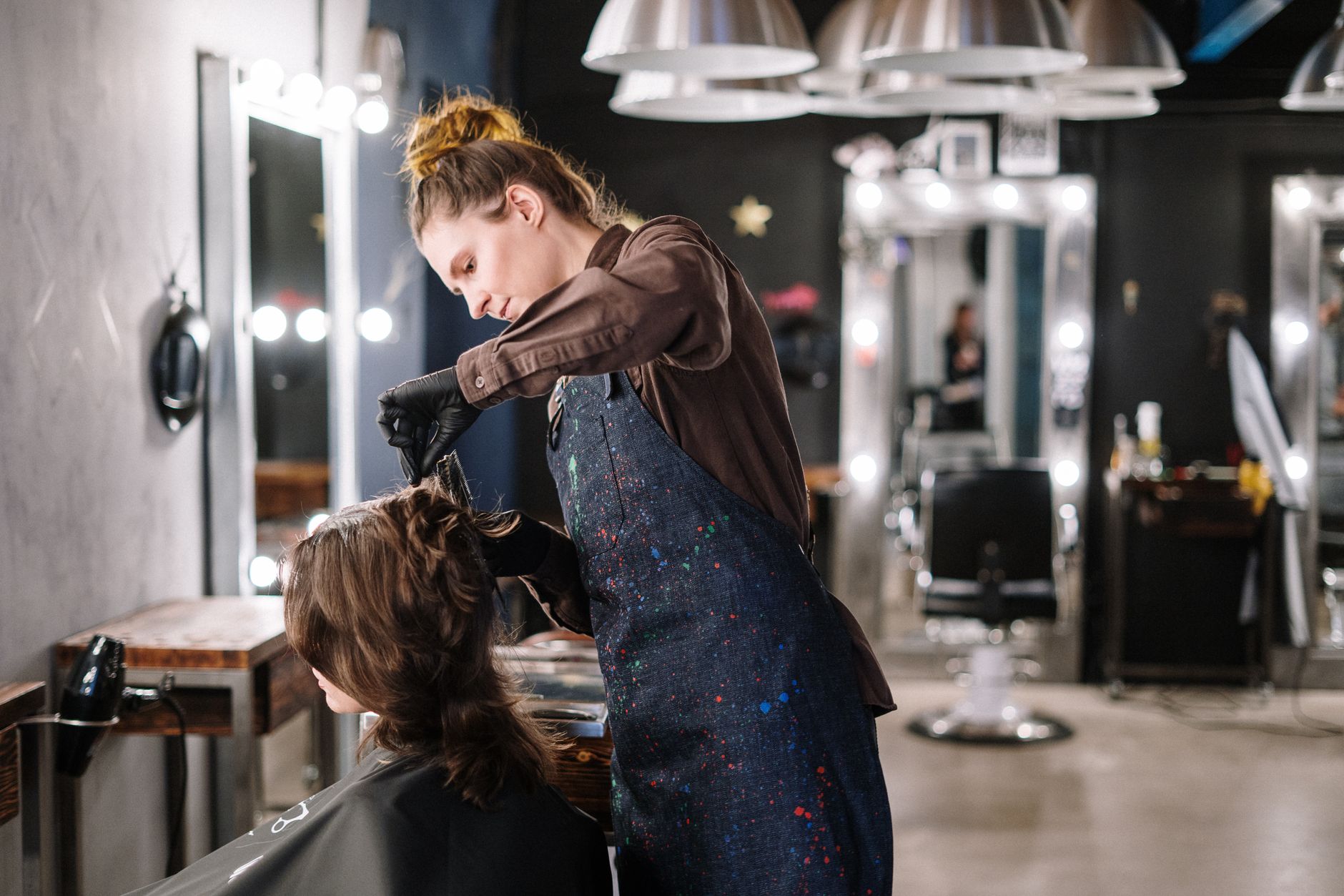 Cabeleireira cortando o cabelo de uma cliente diante do espelho
